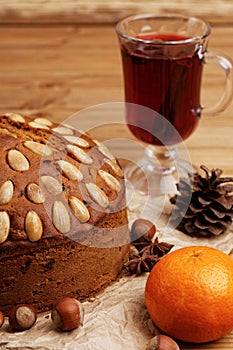 Closeup homemade cake with almonds and glasse with mulled wine on a wooden table.