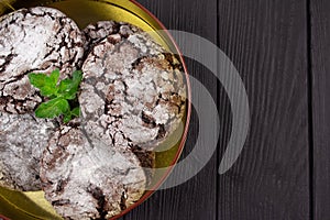 Closeup of homemade chocolate cookies in metal container on black wooden table background with copy space for text or recipe.