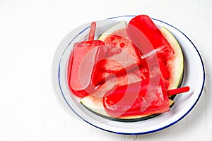Closeup of homemade popsicles on plate with watermelon pieces