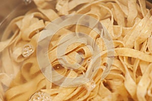 Closeup of homemade raw noodles from spelt dough cooking in boil