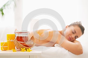 Closeup on honey spa therapy ingredients and woman in background