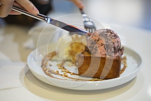 Closeup of Honey toast with strawberry chocolate chip icecream topping with hands holding fork and knife