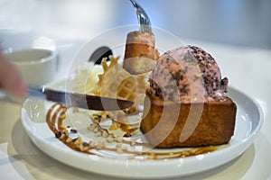 Closeup of Honey toast with strawberry chocolate chip icecream topping with hands holding fork and knife