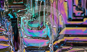 Closeup of hopper crystal of bismuth chemical element in colored iridescent background