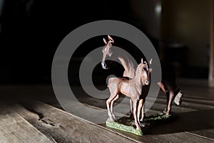 Closeup of horse figurines on wooden floor with low light