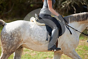 Closeup, horse riding or woman in countryside outdoor with rider or jockey for recreation or wellness. Freedom, saddle