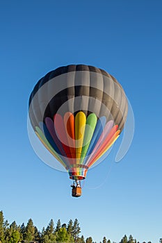 Closeup of a hot air balloon flying over Bend, Oregon against a clear, blue sky