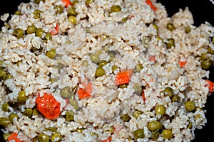 A closeup of hot steamed white rice with vegetables peas and carrots with sliced onion, Chinese cuisine recipe