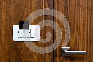 Closeup of hotel room door and lights switch. Key card in electronic lock