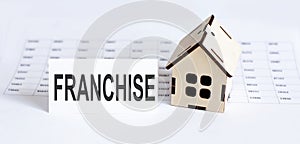 Closeup of house wooden model with blank for text FRANCHISE . on the chart background