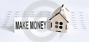 Closeup of house wooden model with blank for text Make Money. on the chart background