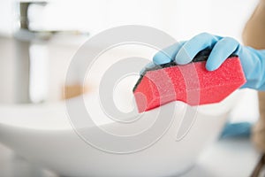 Closeup on housewife cleaning sink with sponge