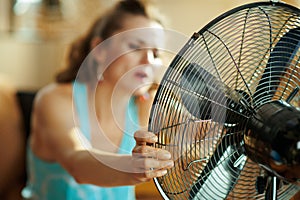 Closeup on housewife using fan suffering from summer heat