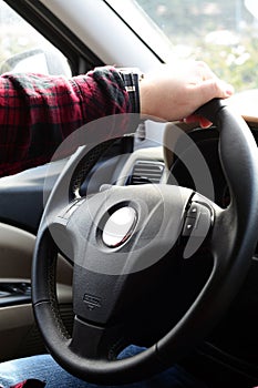 Closeup of human hand holding car steering wheel