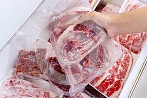 Closeup of human hand picking a pile of red meat