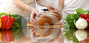 Closeup of human hands cooking in kitchen. Mother and daughter or two female friends cutting bread for dinner