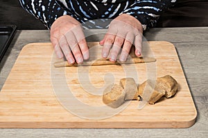 Closeup of human hands working with raw nutty shortbread dough on wooden rolling board