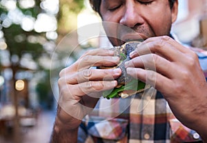 Hungry man sitting outside eating a delicious poppy seed bagel photo
