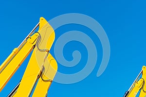 Closeup hydraulic piston of yellow backhoe against blue sky. Heavy machine for excavation in construction site. Hydraulic machine