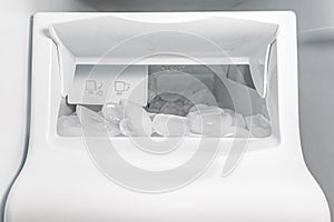 Closeup of ice maker, ice machine in refrigerator with ice cubes photo