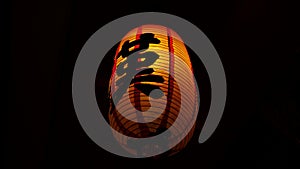 Closeup of an illuminated Chinese lantern/lamp with the letter `KA` written in Chinese shaking in the wind