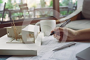 Closeup image of architects drawing shop drawing paper with architecture model