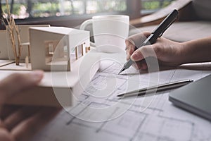 Closeup image of architects drawing shop drawing paper with architecture model