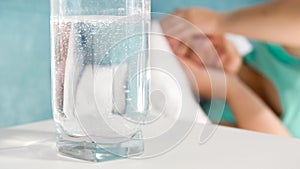 Closeup image of aspirin dissolving in glass of water