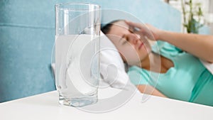 Closeup image of aspirin pill dissolving in glass of water on bedside table