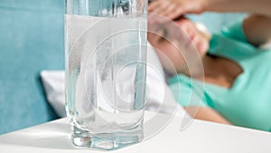 Closeup image of aspiring painkiller dissolving in glass of water on bedside table