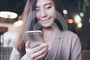 Closeup image of a beautiful Asian business woman with smiley face using and looking at smart phone