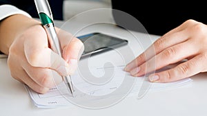 Closeup image of businesswoman putting signature on banking payment cheque