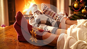 Closeup image of couple with child wearing knitted socks relaxing by the fire at house photo