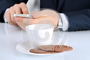 Closeup image of Cup of coffee with cookies .Businessman holdin
