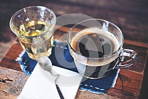 Closeup image of cups of hot coffee and tea on vintage wooden table in cafe with blur woman using smart phone