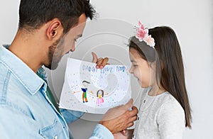 Closeup image of a cute daughter giving a greeting card for his smiling father on holiday for Father`s day. Loving daddy and his