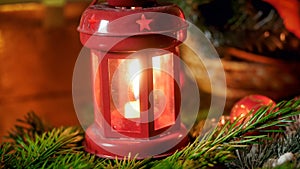 Closeup image of decorative lantern with burning candle on Christmas tree branch