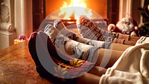 Closeup image of family in knitted woolen socks warming by fireplace