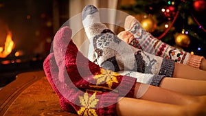 Closeup image of family in warm knitted socks lying next to fireplace and Christmas tree