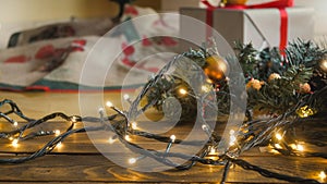 Closeup image of glowing lights garland for Christmas lying on wooden floor