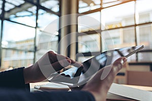 Hands holding and pointing at a black tablet pc screen in office