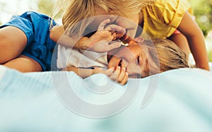 Closeup image of happy children playing on the blanket outdoors. Happy little boy and cute little girl relaxing in the park. Kids