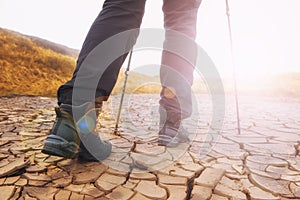 Closeup image of hiker legs in a touristic boots wallking forward on the dry cracked ground