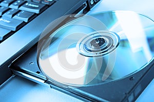 Closeup image of a laptop and a CD / DVD disc