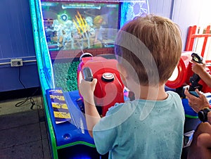 Closeup image of little toddler boy playing in video arcade games at entertainment park