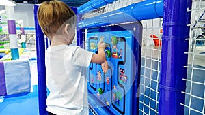 Closeup image of little toddler boy solving puzzle on the children palyground at amusement park. Concept of smart kids