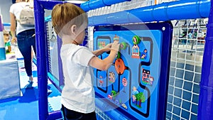 Closeup image of little toddler boy solving puzzle on the children palyground at amusement park. Concept of smart kids photo