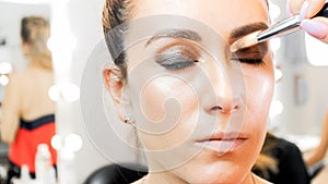 Closeup image of makeup artist painting models eyes with brush