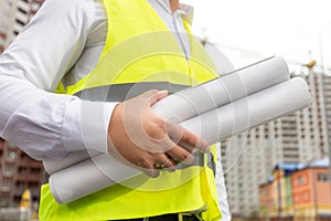 Closeup image of male architect holding blueprints of new houses