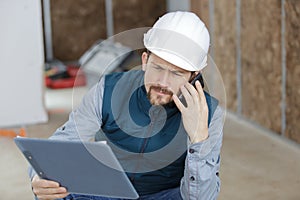 closeup image with male builder holding tablet and phone
